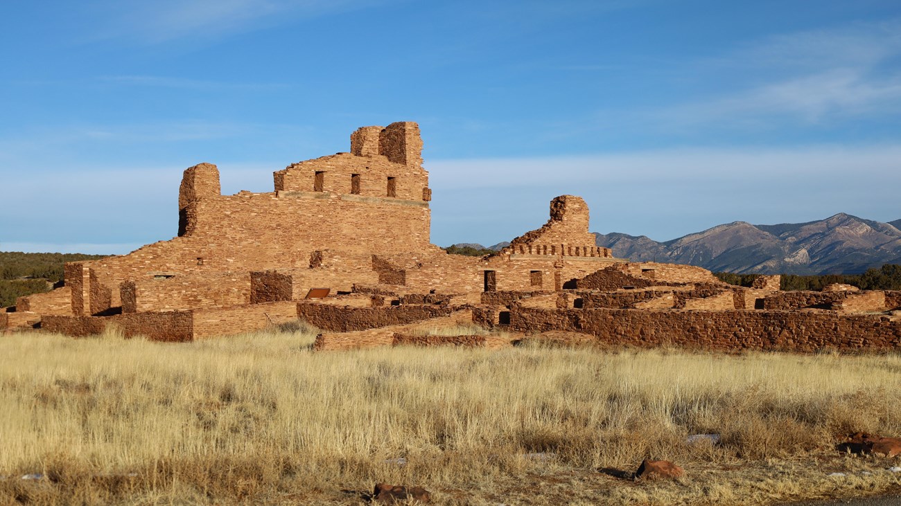 Red sandstone church ruins with mountains in the background