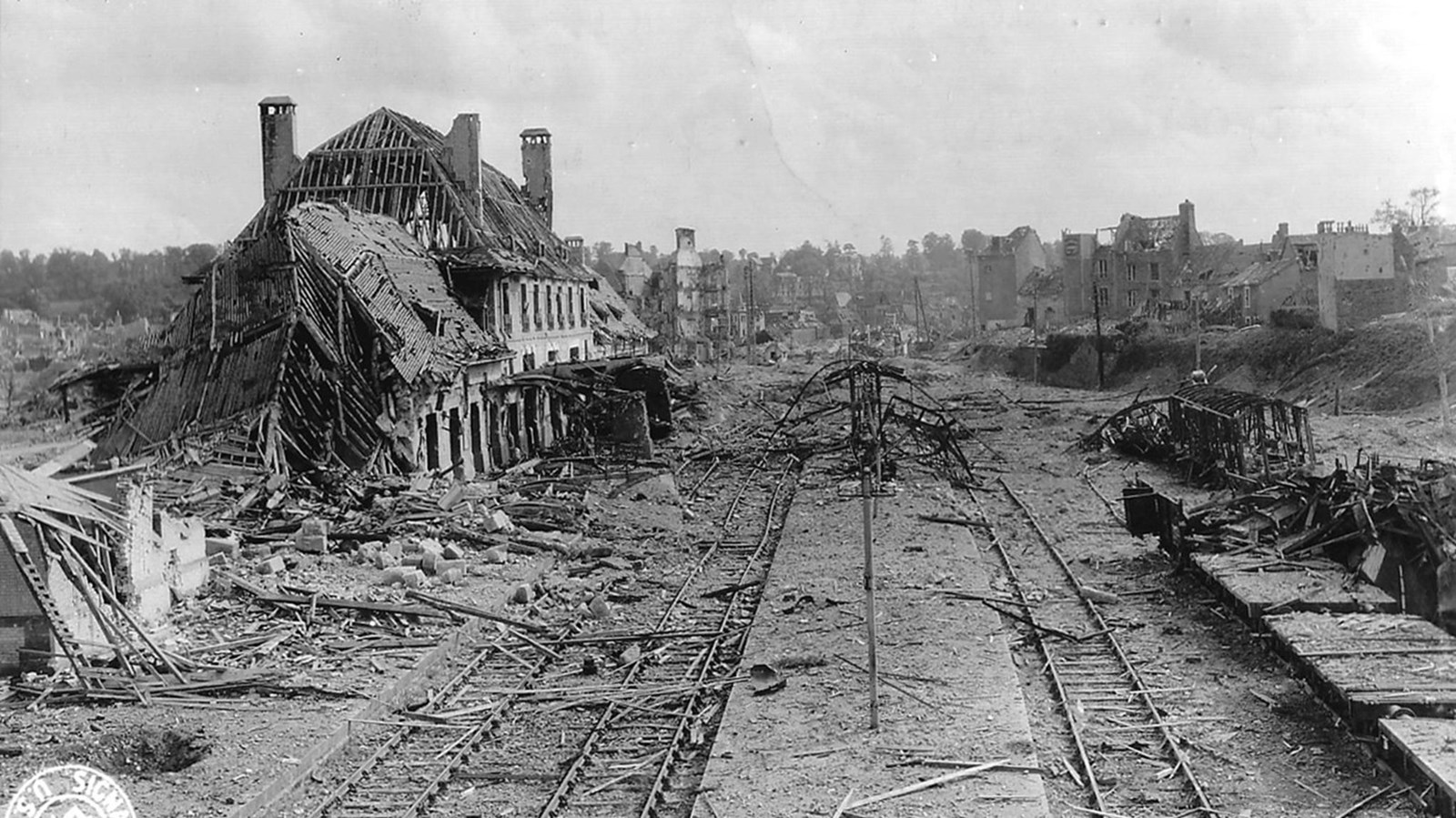 Railroad tracks surrounded by damaged structures and debris.
