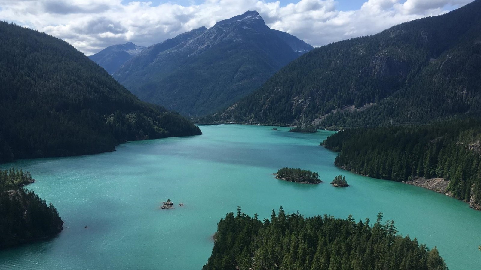 A blue lake surrounded by forested mountains.