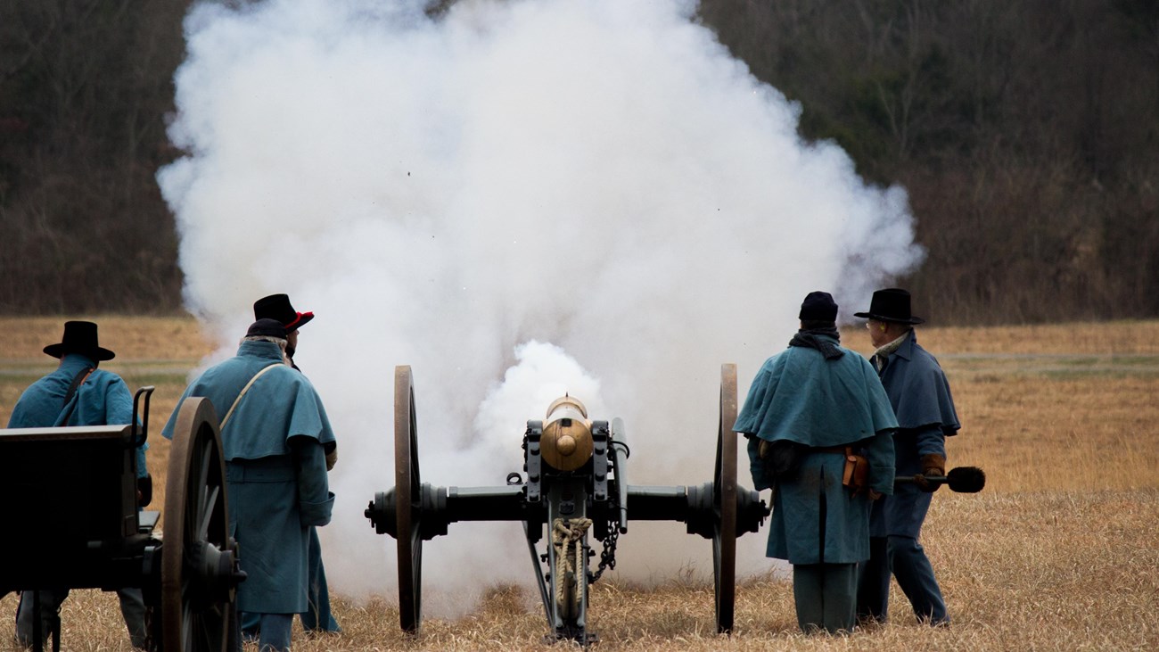 Men in blue wool uniforms fire a bronze cannon.