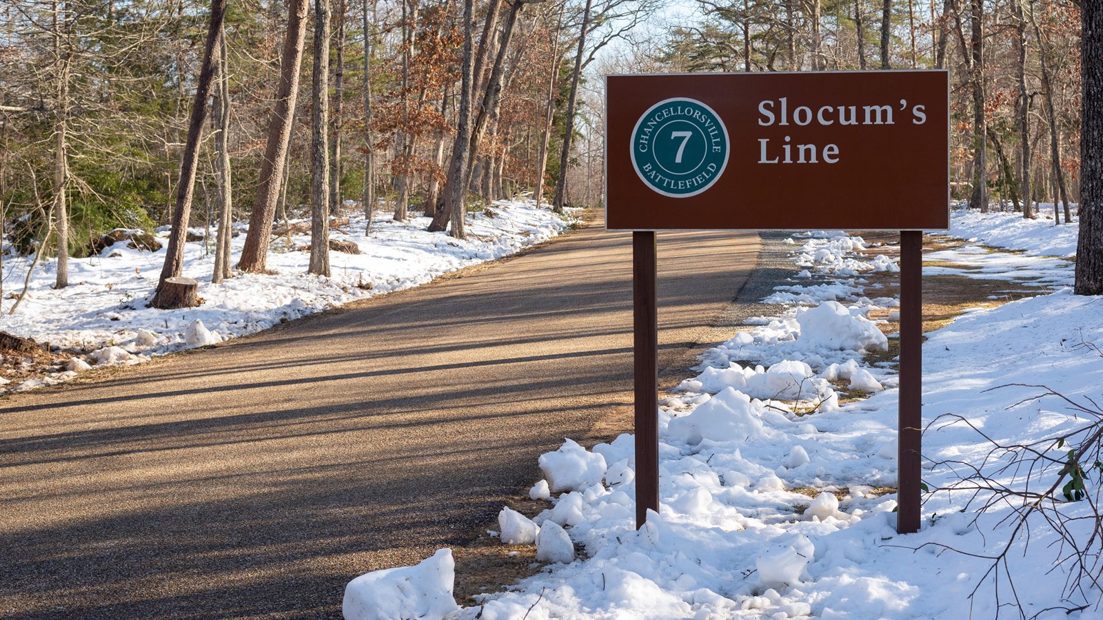 A brown sign for Slocum\'s Line along a paved road.