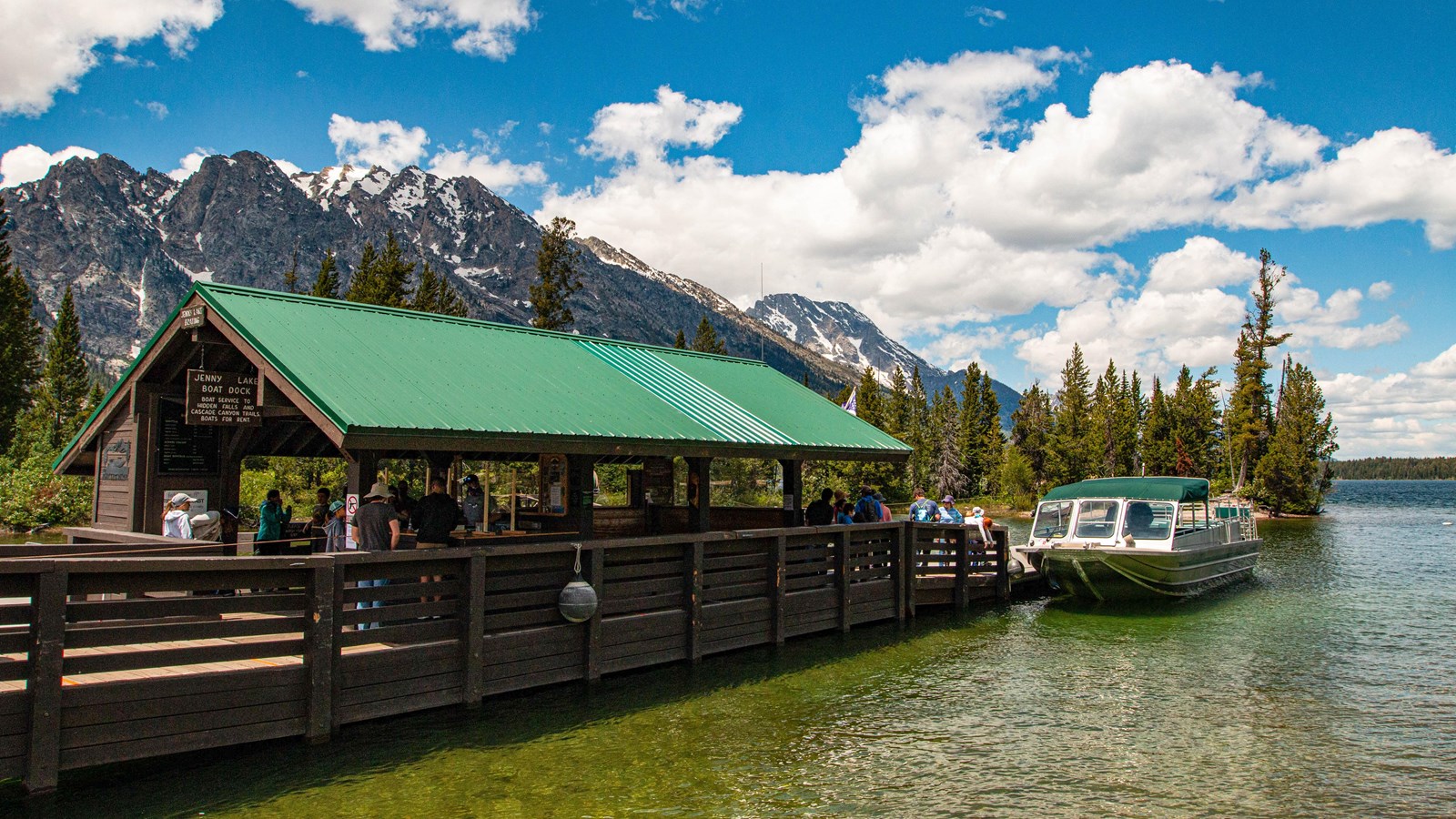 Jenny Lake East Shore Boat Dock, boat, and passengers buying tickets. Mountains in the background. 