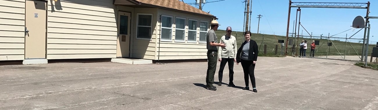 A park ranger with visitors inside a fenced compound