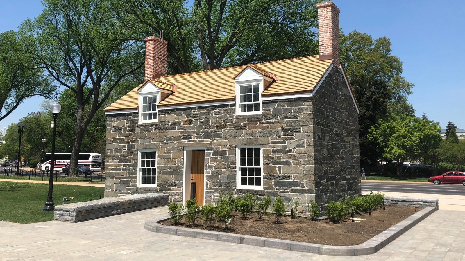 A two-story stone building on a plaza of stone pavers