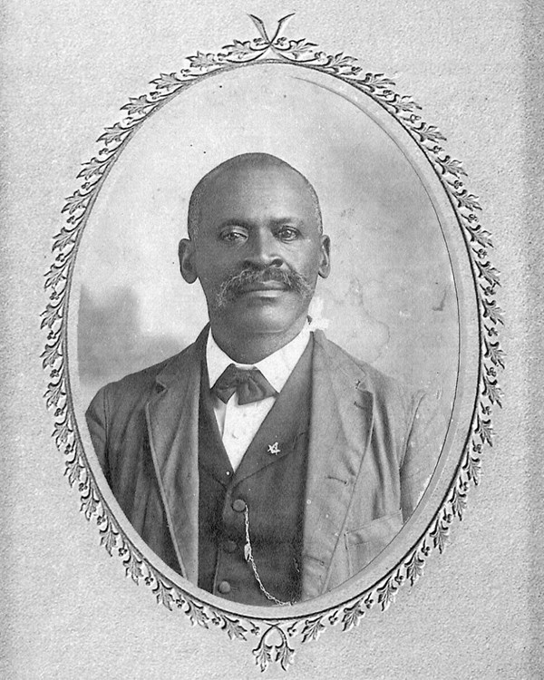 Portrait of bald black man with bushy mustache in a suite.