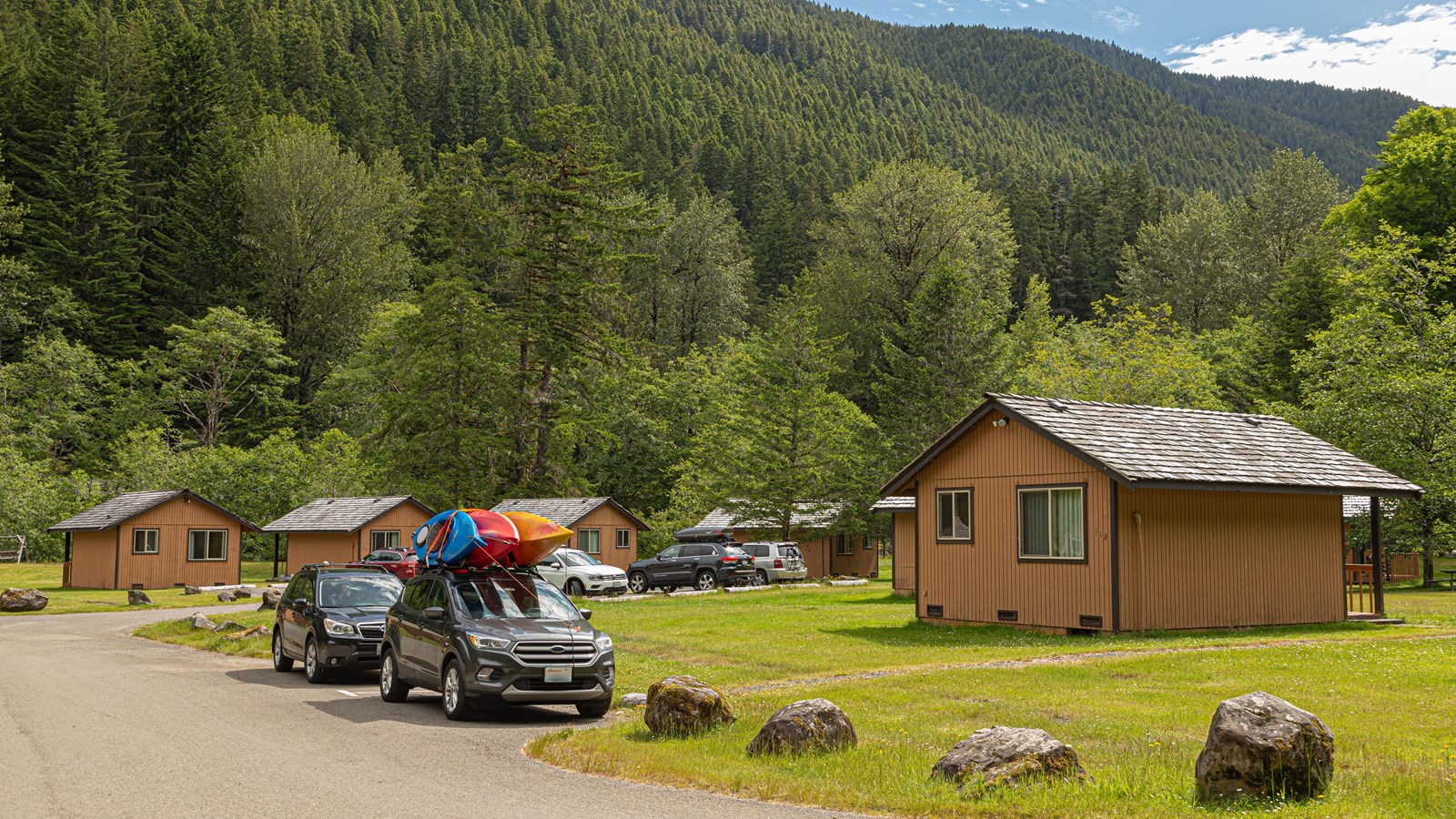 Cars and cabins, with a forested mountain in the background.