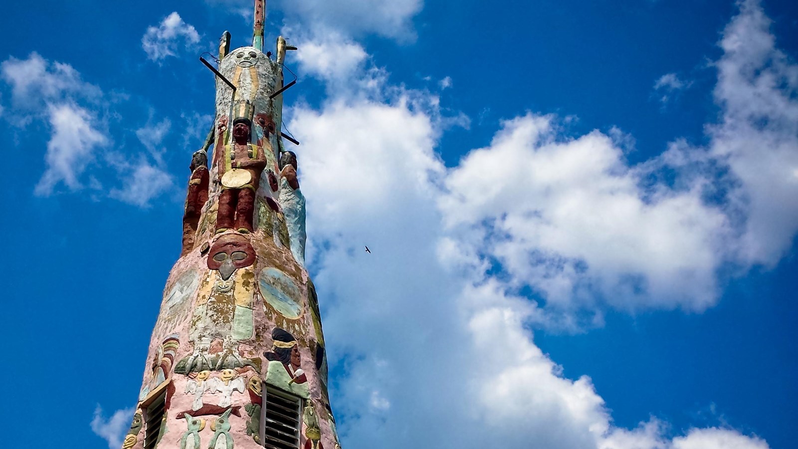 A 90 foot tall plaster totem pole with faces and representations of Native American art on it. 