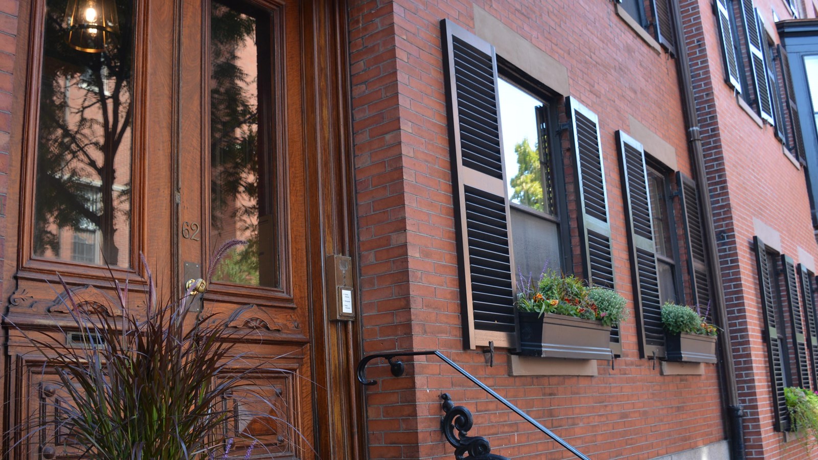 An angled photograph of the entrance of the brownstone with the wooden front door on the left. 