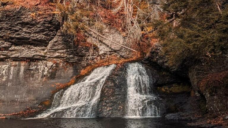 A small waterfall with fall foliage around it.