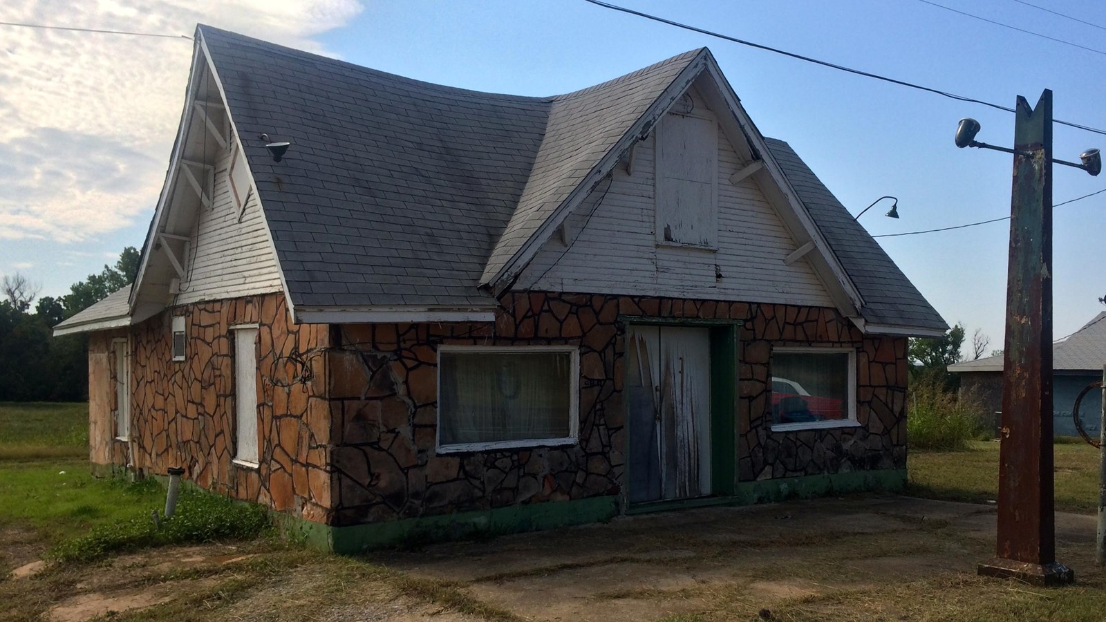 A stone building with a gabled roof and white siding.