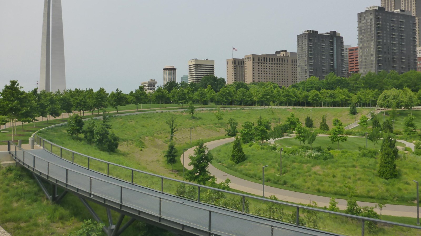 A green space with the city and gateway arch in the background