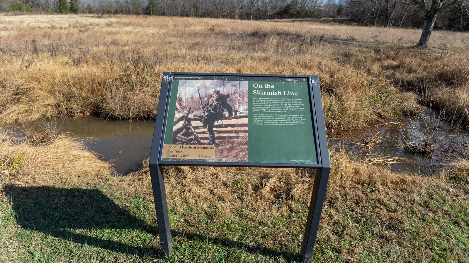 A painting of a soldier climbing over a wood fence holding a gun is displayed. 