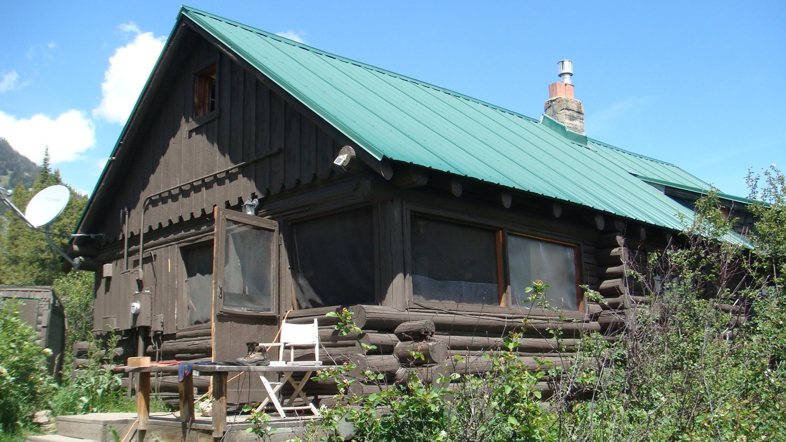 A brown wooden cabin with a green roof.