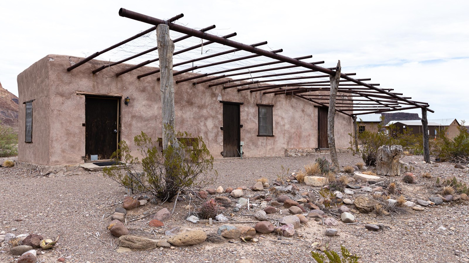 2-room adobe structure with a metal ramada over the front doors