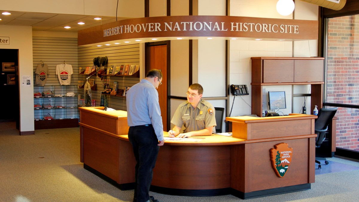 A ranger at an information desk assists a park visitor.
