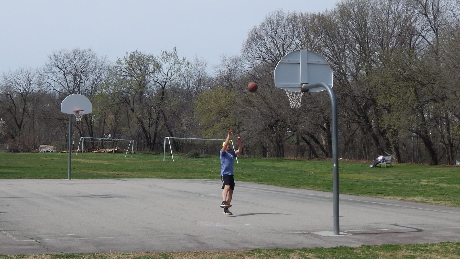 A basketball court with two hoops and a player taking a shot on the near hoop