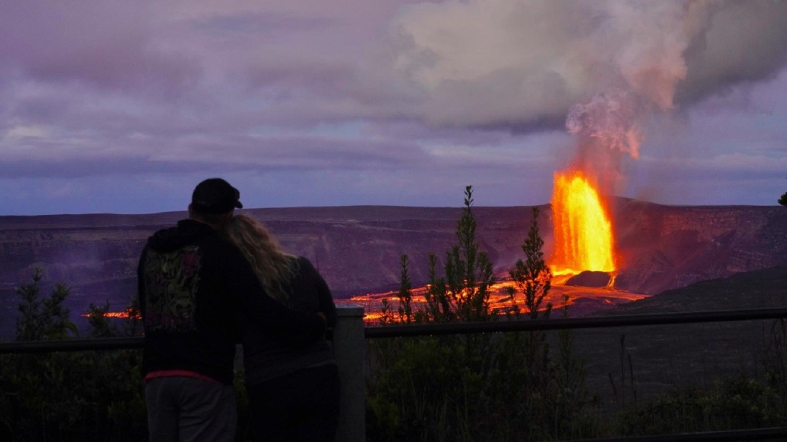 A couple views an eruption at night.