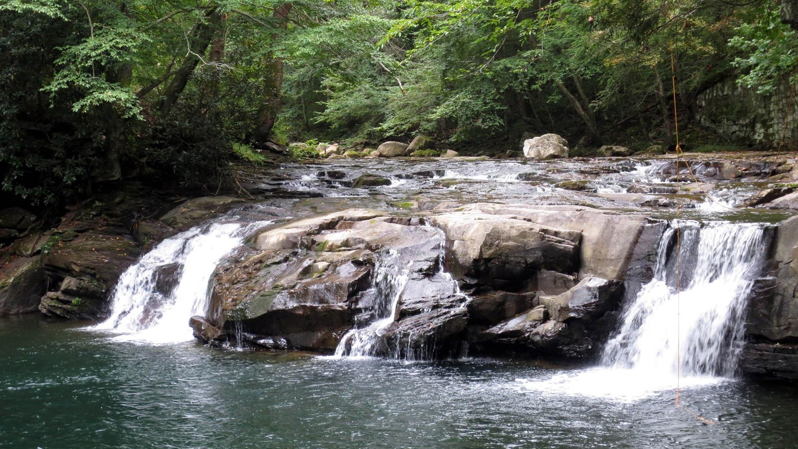 A view of a waterfall into a deep pool along the trail.