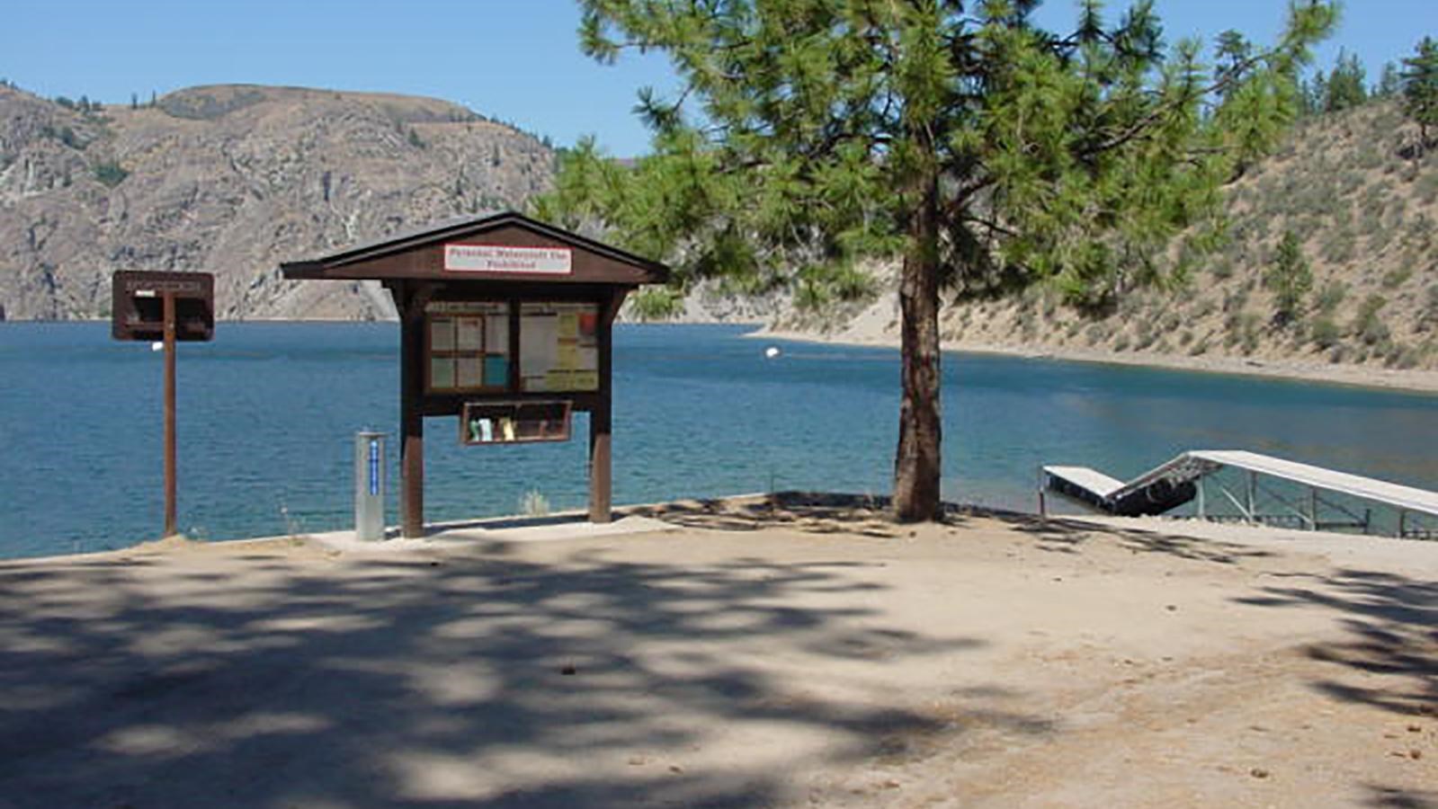 The dirt road and parking area at the paved boat launch, dock in view.