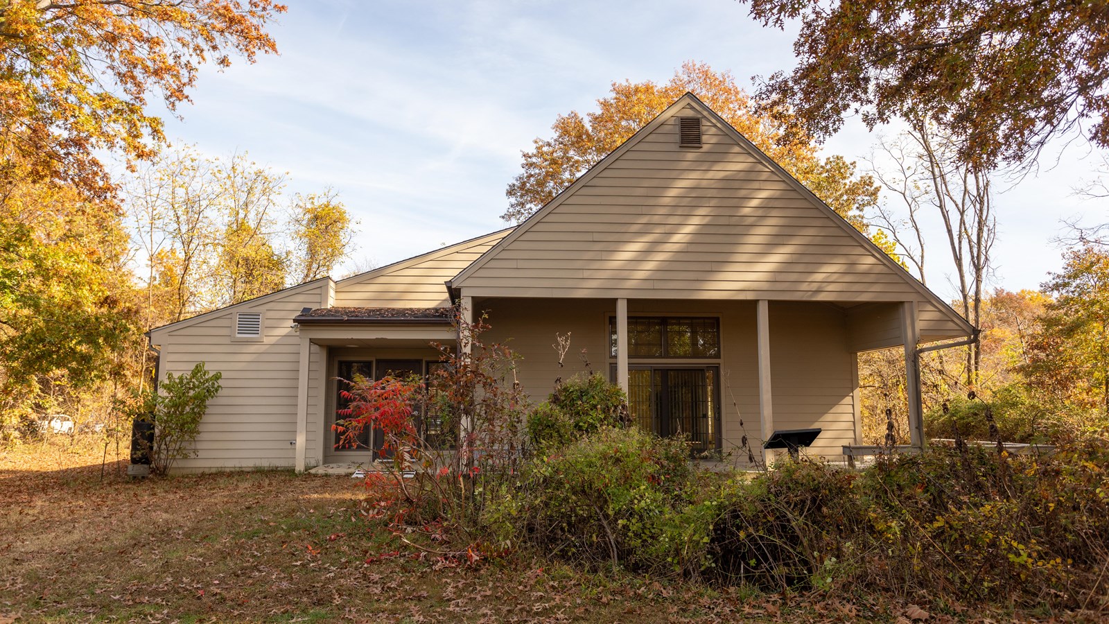 A one and a half story light grey building with a covered patio