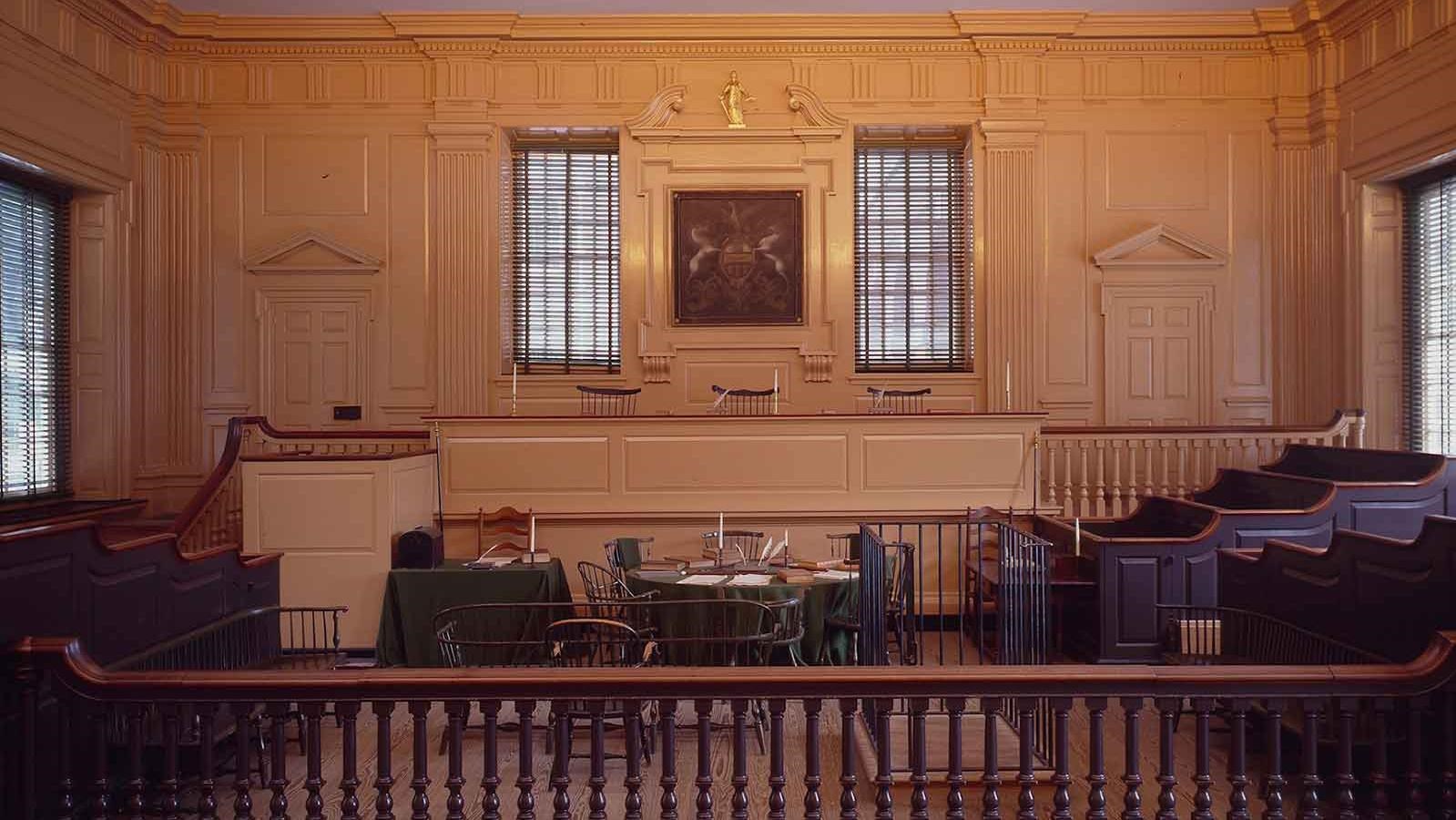 Interior view of a courtroom showing a judges\' bench, jury boxes, and table for lawyers.