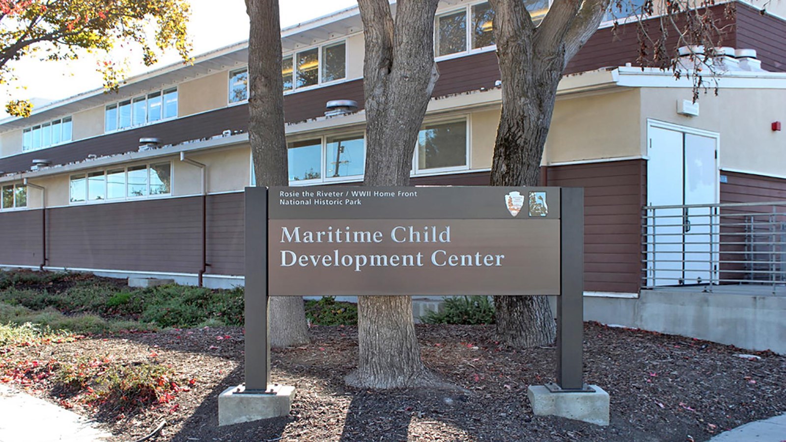 Photo of park sign and corner of building. 