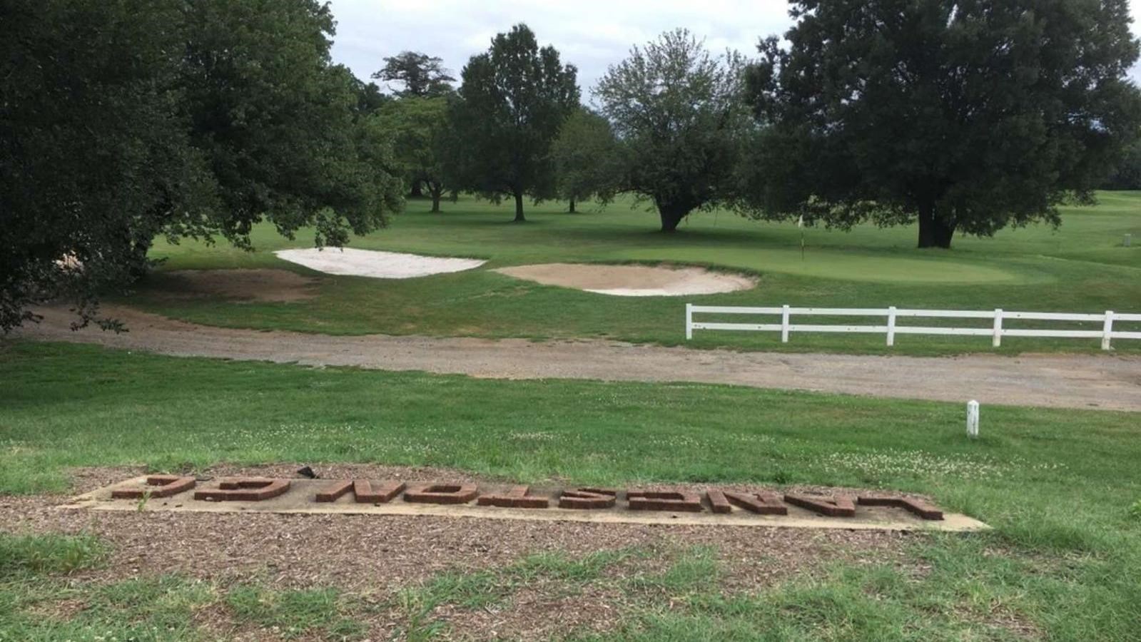 A golf course with sand pits and trees