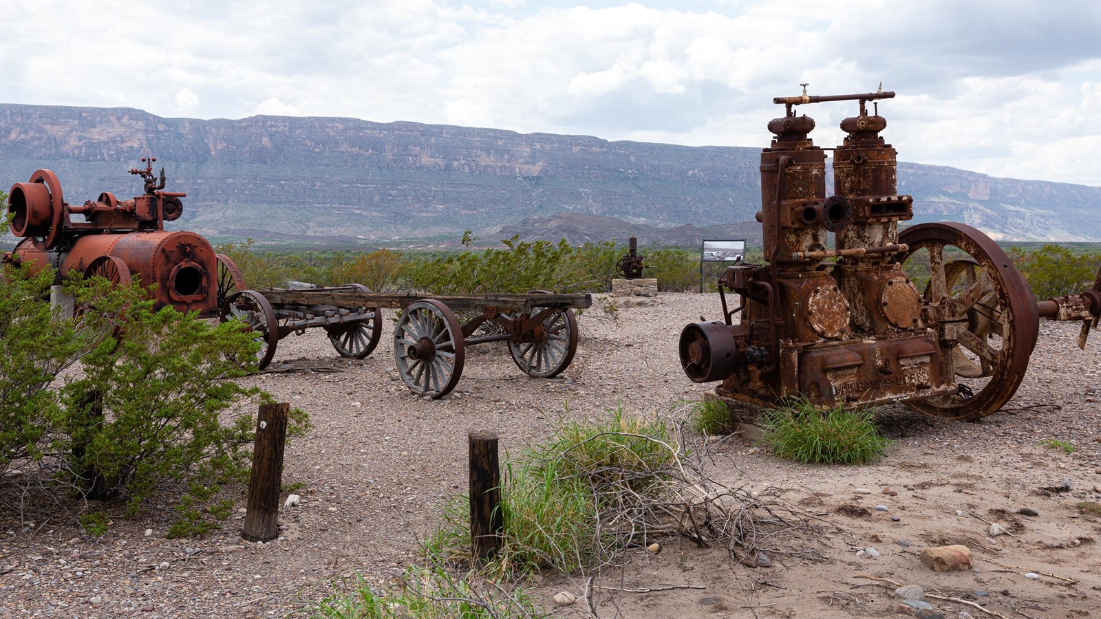 A rusted water pump and machinery from a cotton gin sit on the edge of a mesa.