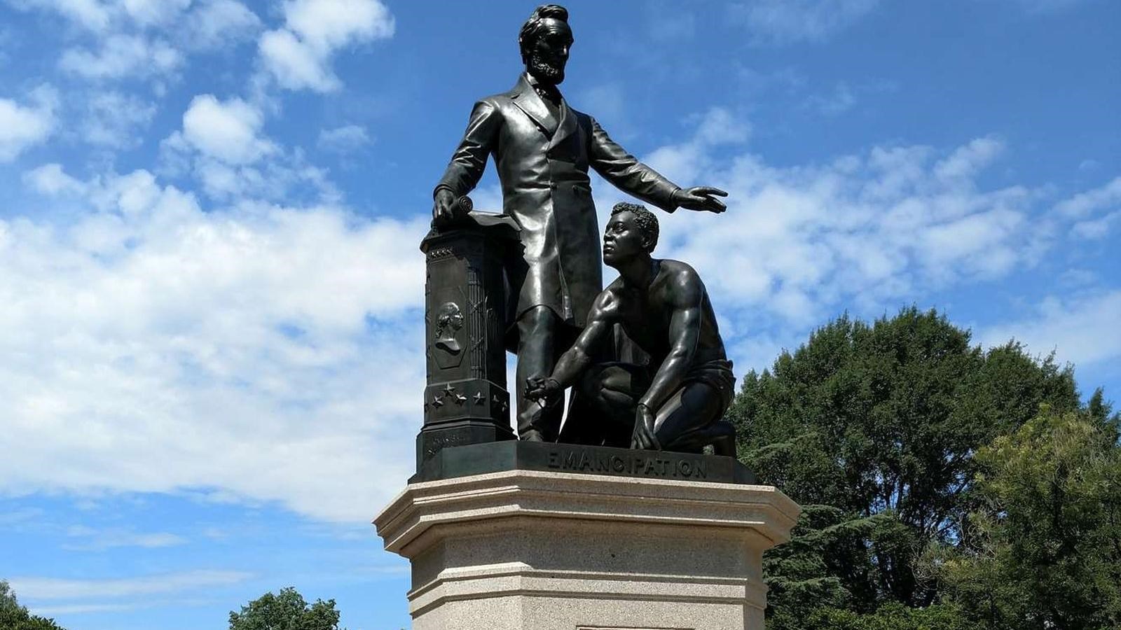 Bronze statue of Abraham Lincoln standing over a freed slave who is kneeling and looking up.