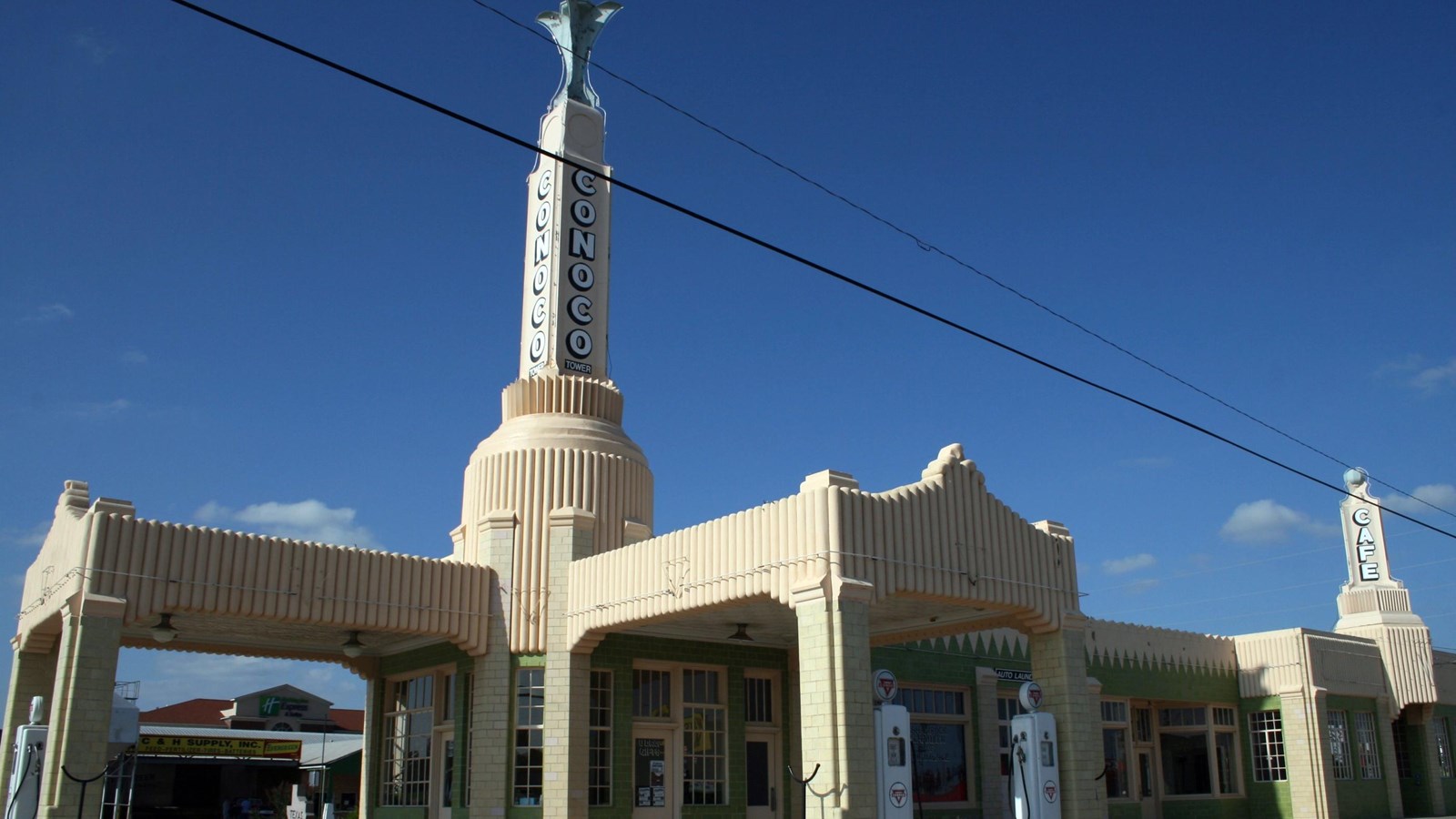 Filling station made of light pink concrete with spire on top.
