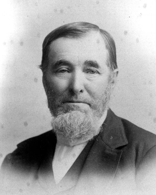 An 1880s portrait photo depicts a man with a grey chin beard.