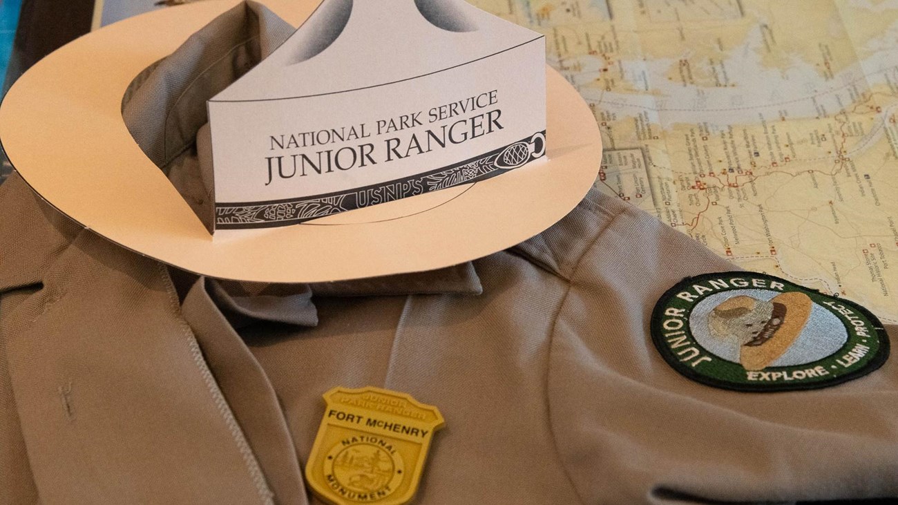 A shirt with a junior ranger patch, badge, and hat sitting on top of it.