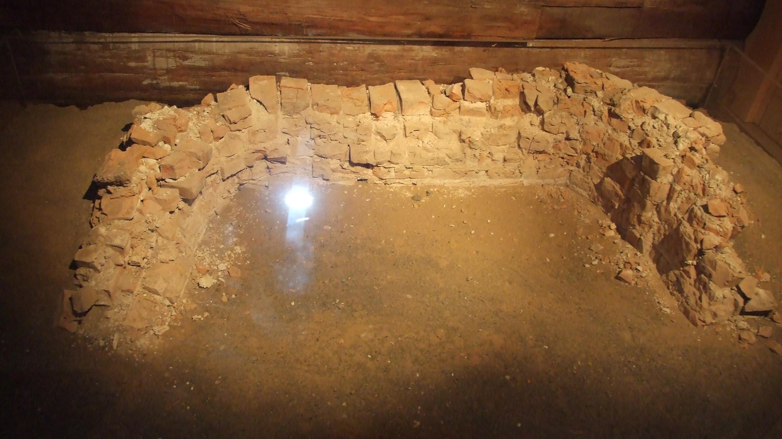 A C-shaped structure made of bricks stands about 2 feet high. The edges are crumbling. 