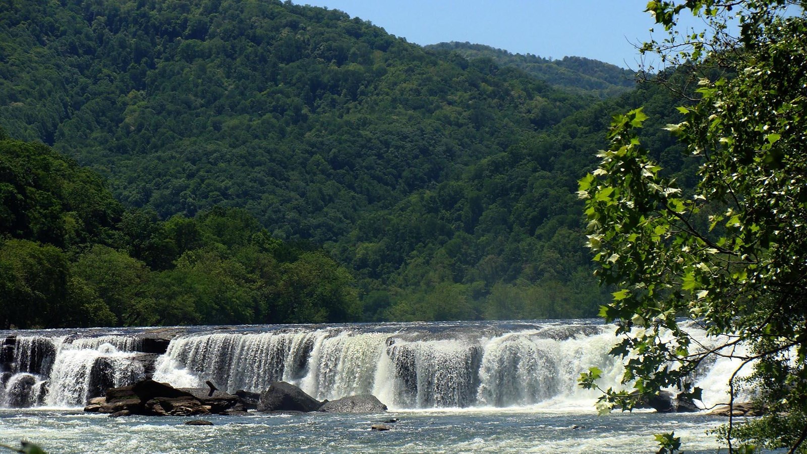 A large waterfall spanning across a wide river
