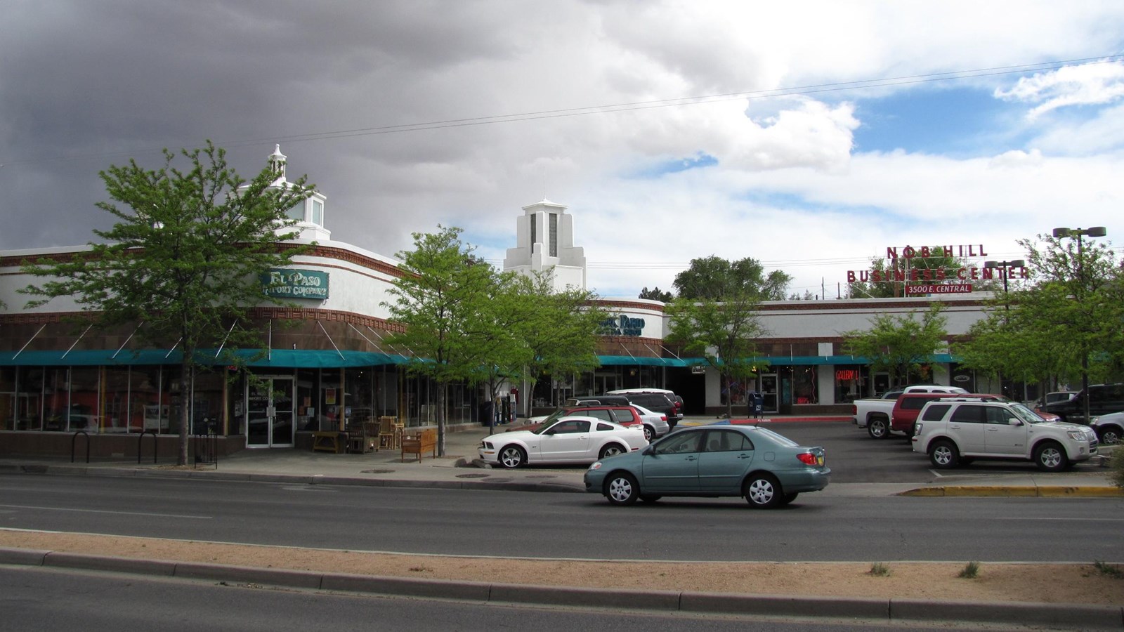Moderne style center has white-stuccoed walls, architectural neon, decorative brick courses.