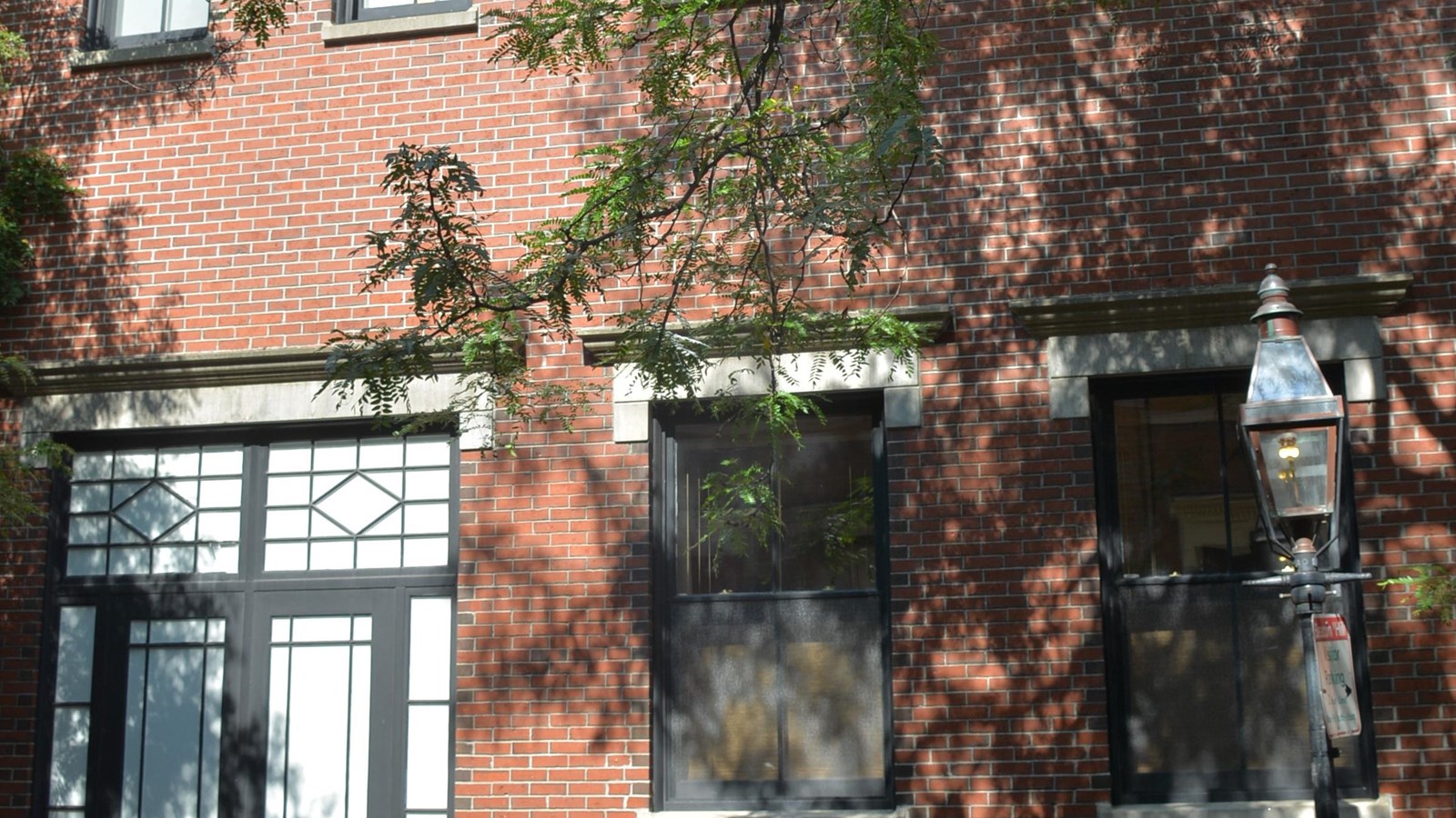 The first floor of a red-brick building. Two windows are on the right and a door is to the left.