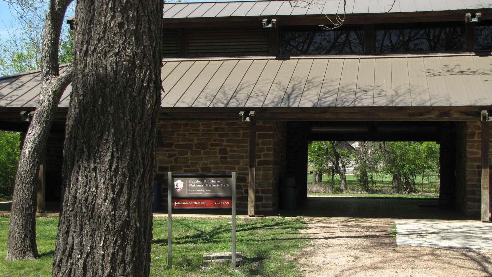 A large, stone building with a two-tiered roof and a wide, dark breezeway has a park sign our front.