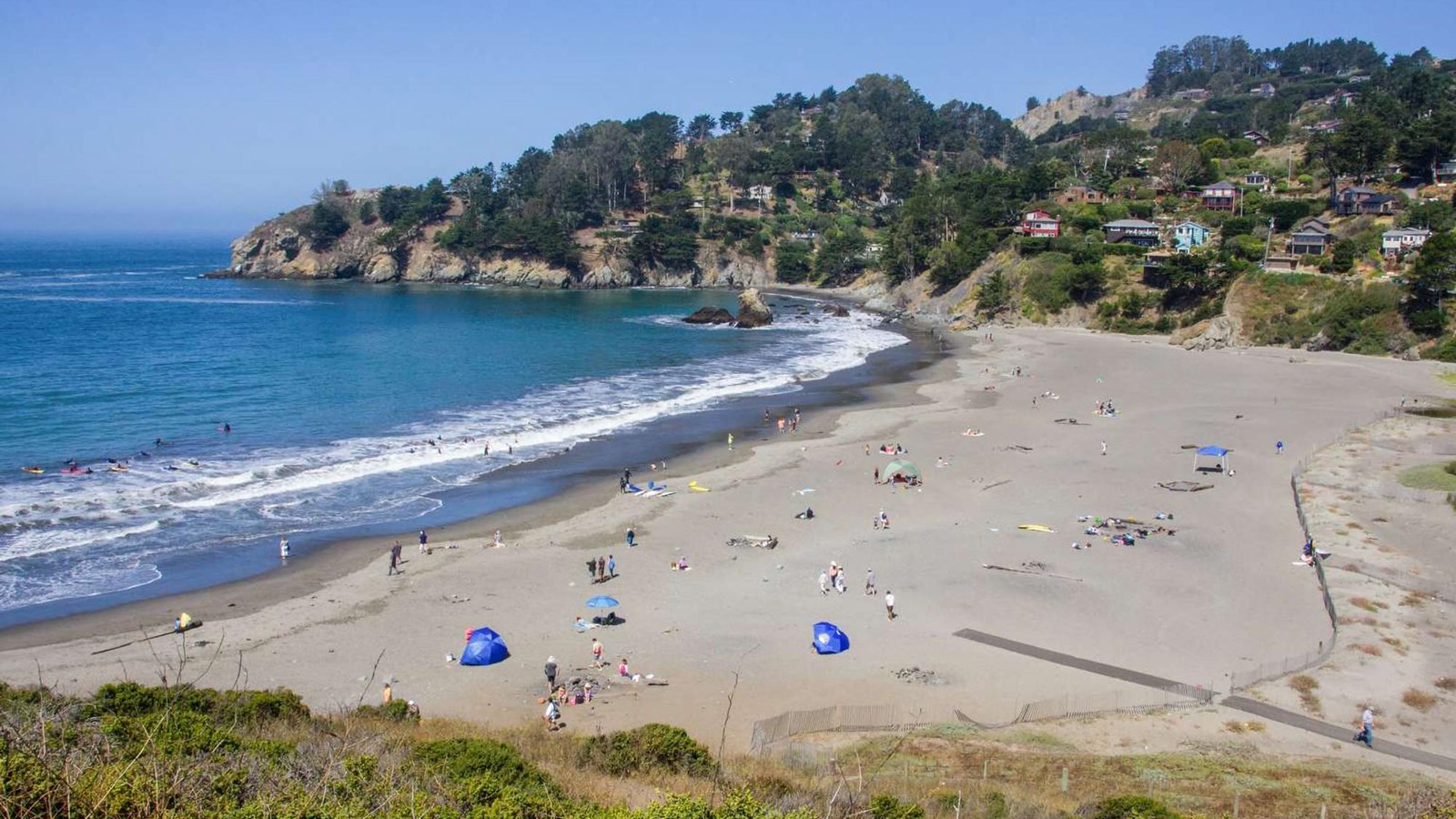 A sunny day looking down on Muir Beach filled with visitors enjoying the beach.