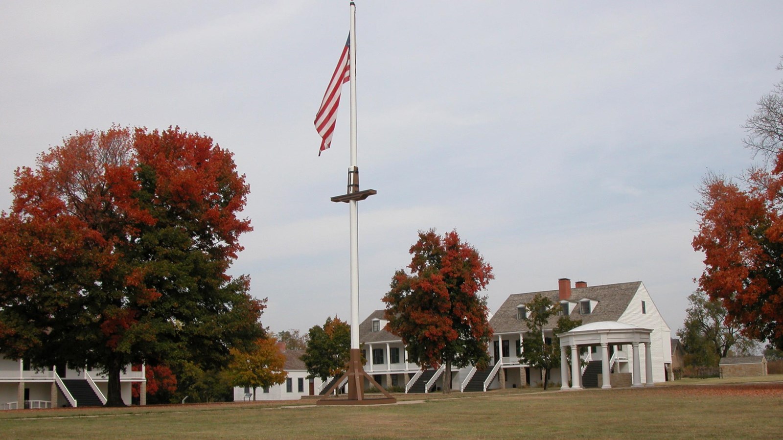 US Flag on Flag pole with trees on parade ground