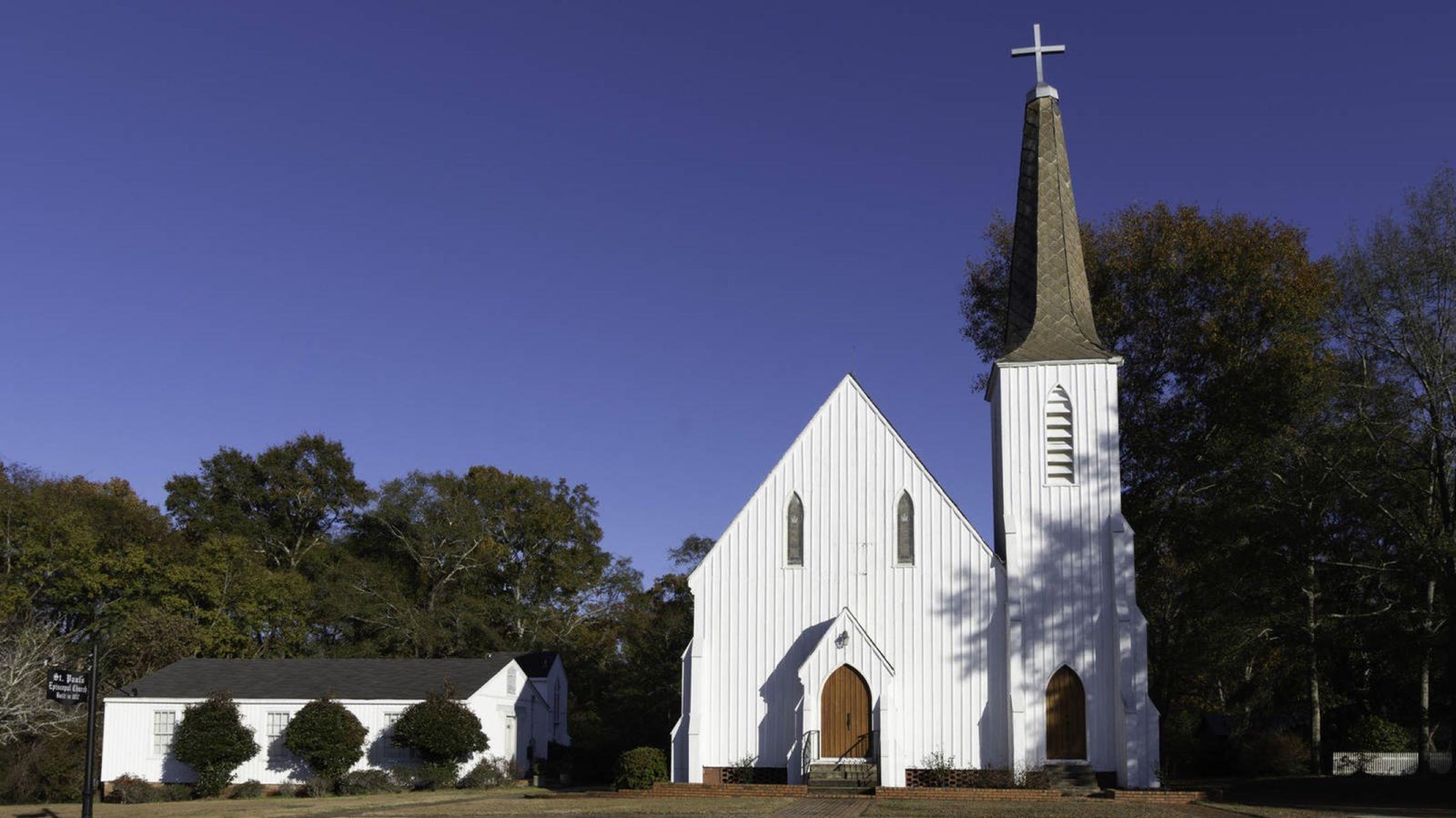 White church with steeple surrounded by trees and blue sky 