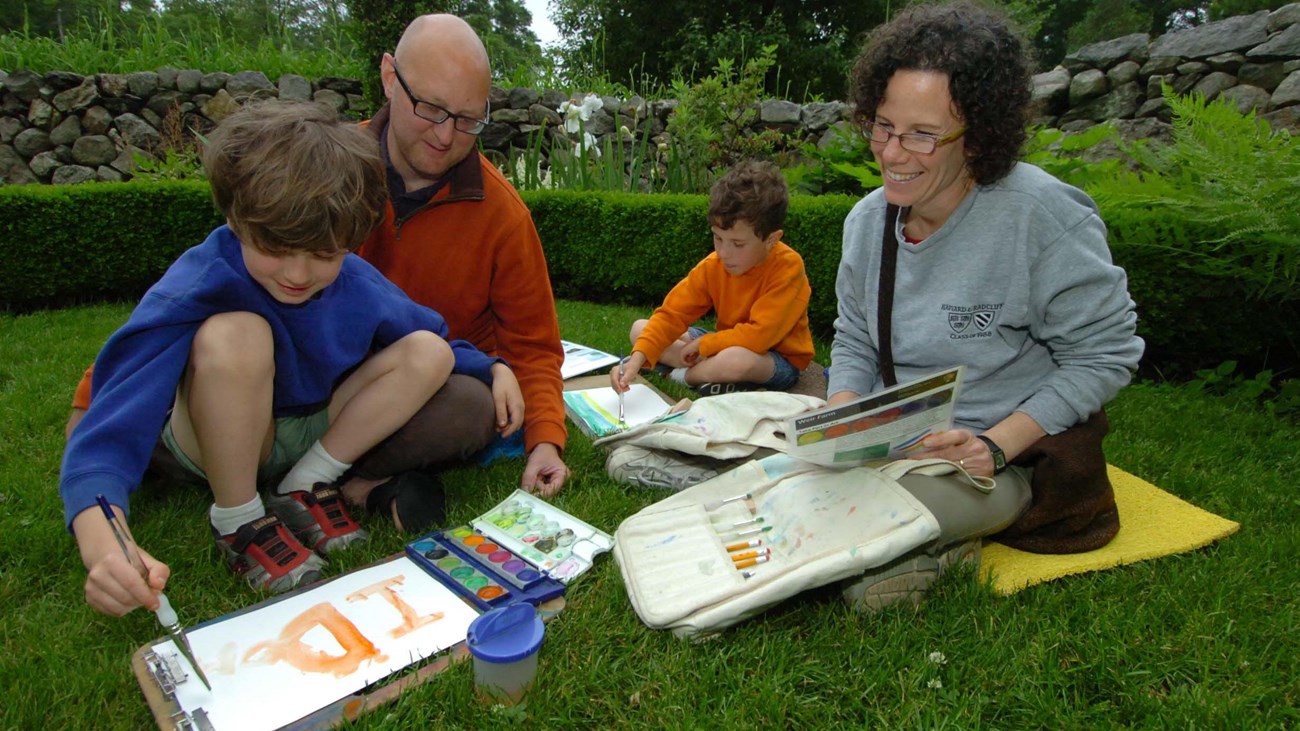 A family sitting in the grass painting.