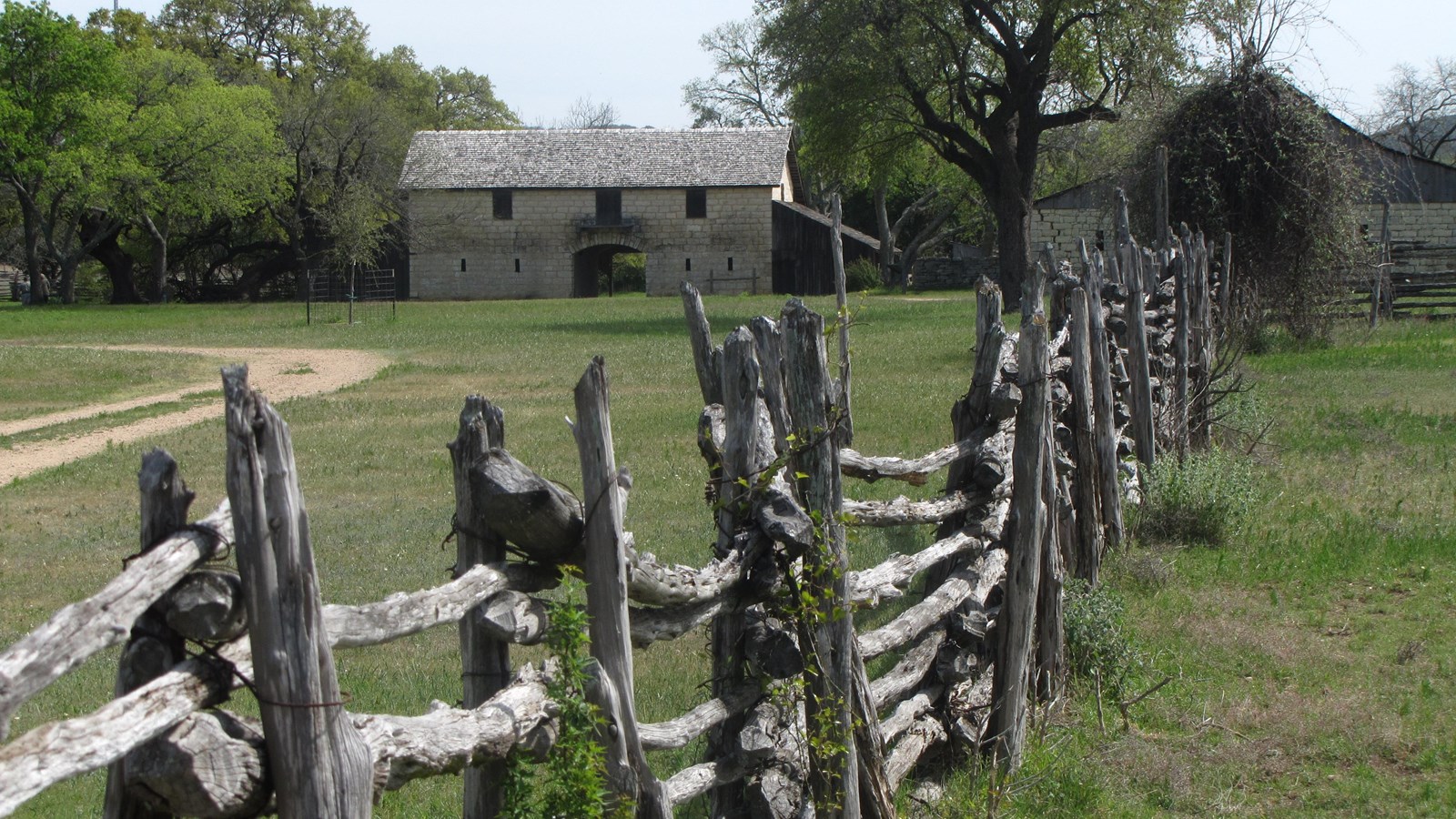 An old, pioneer fence stretches into the distance towards historic structures.