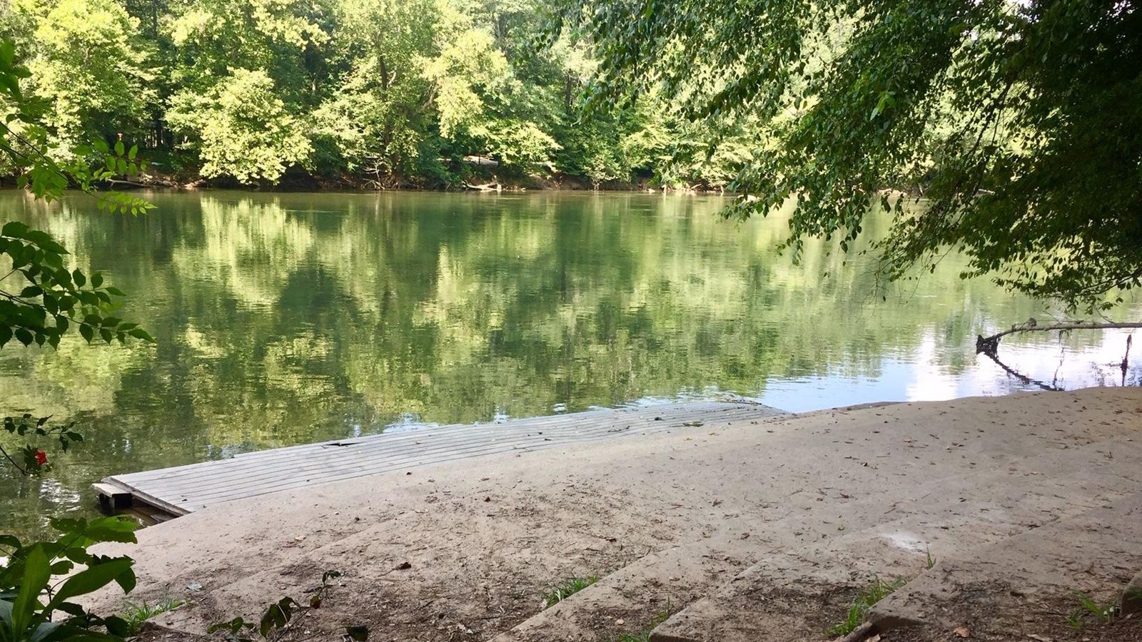 View of steps leading to rivers edge with wooded shoreline in the distance.
