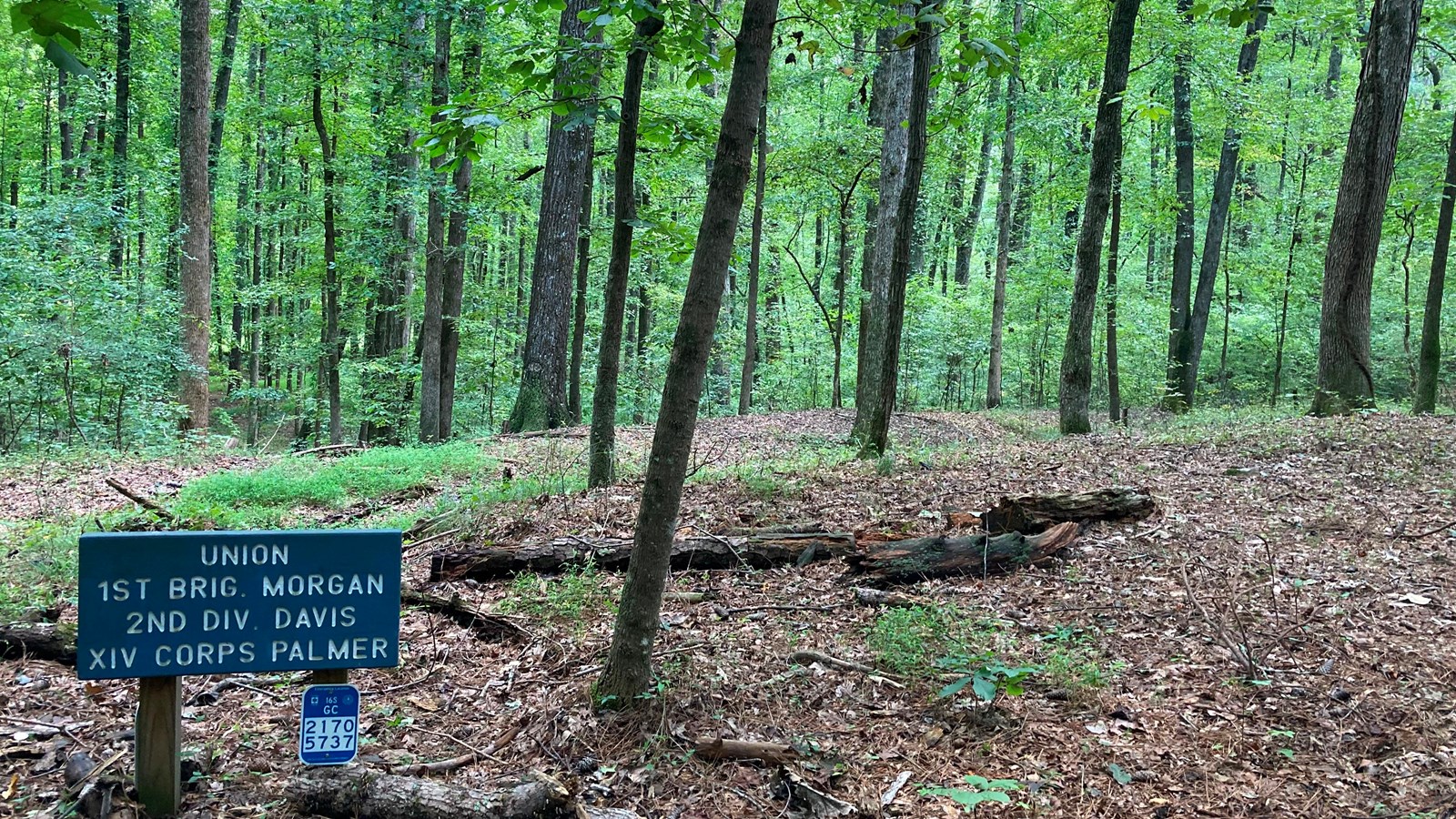 A small blue sign stands in front of a large earthen trench