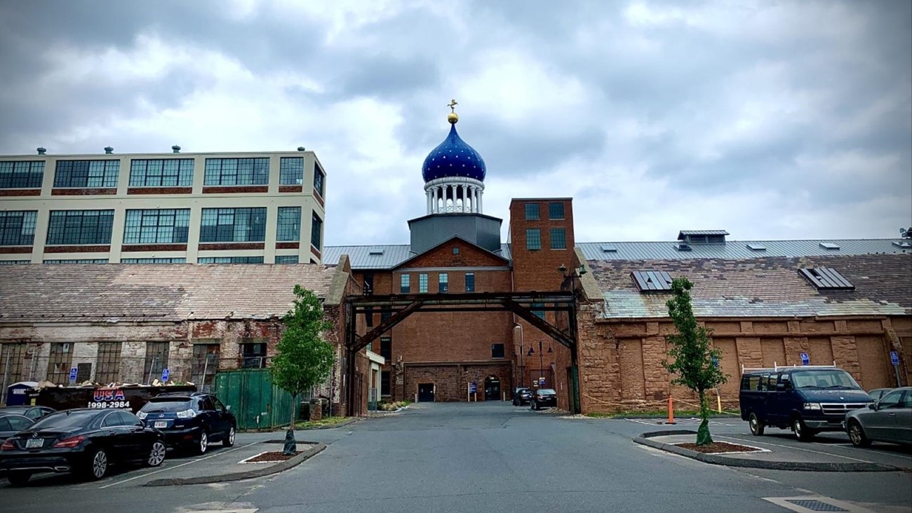 The Colt Dome between the two brownstone buildings on a cloudy day