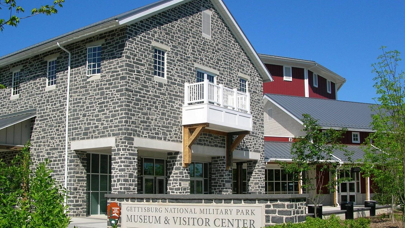 A large stone building with a red barn structure in the background