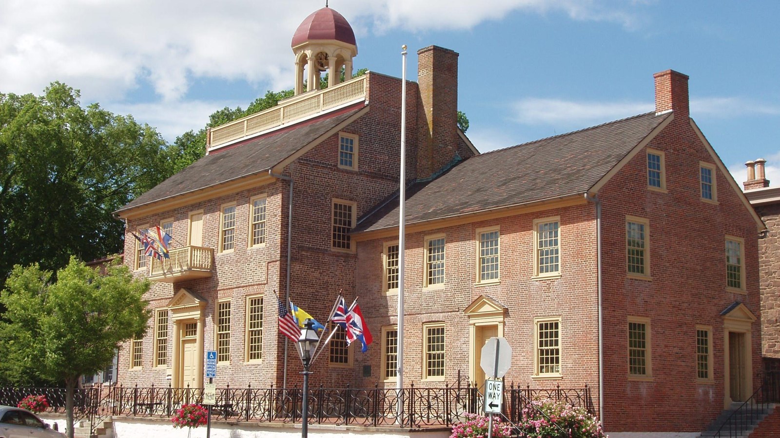 An angled view of a brick building with three wings, the middle being the tallest.