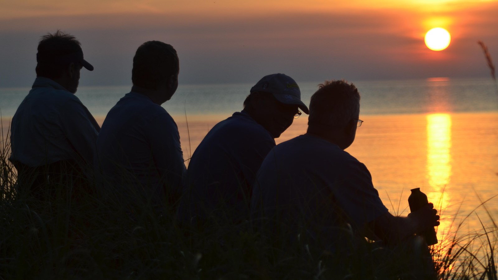 Four men silhouetted against orange sunset