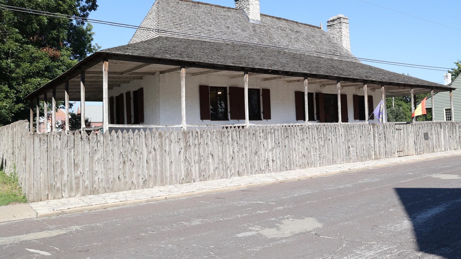 White house with brown roof and tall wooden fence.