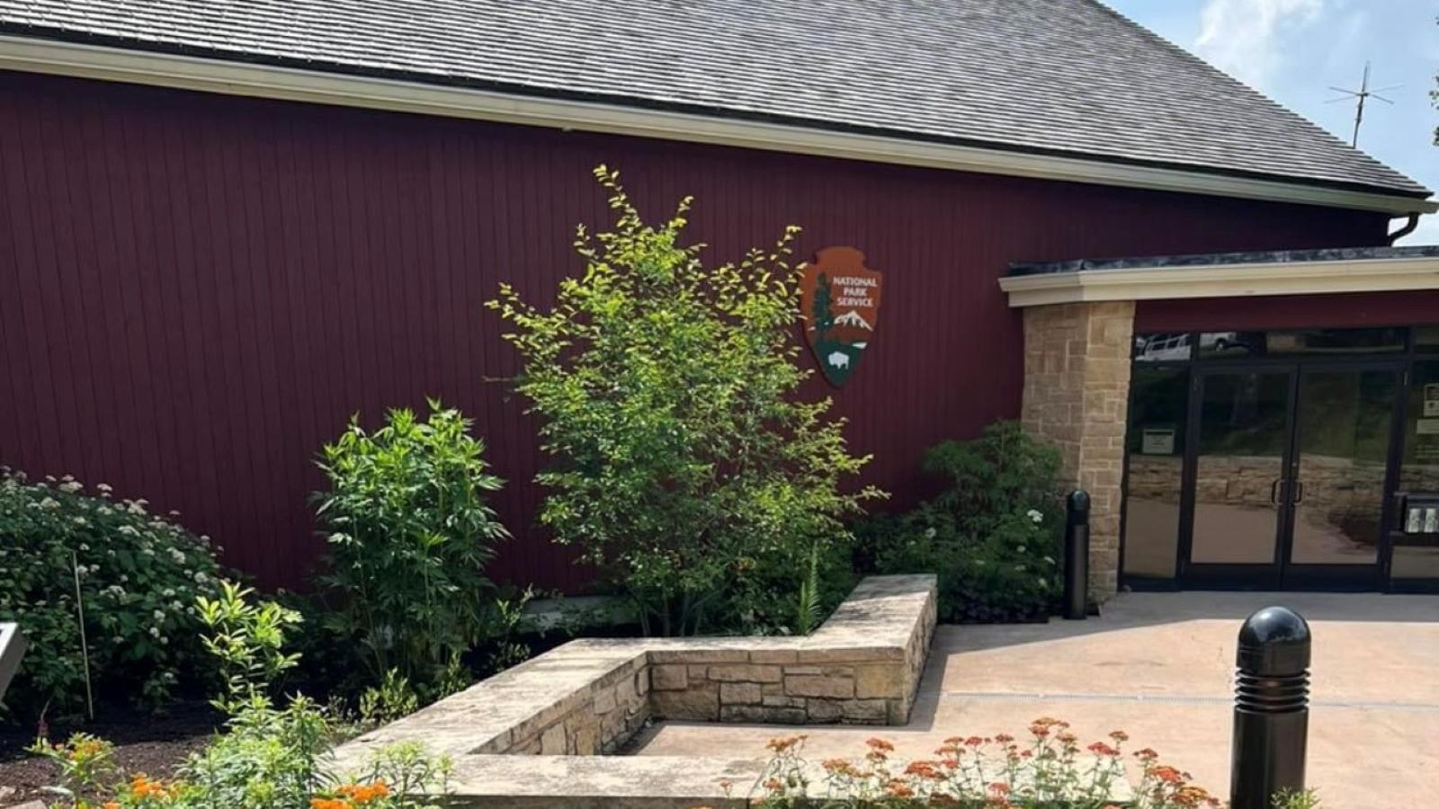 A garden with native plants and a structure that resembles a red barn.